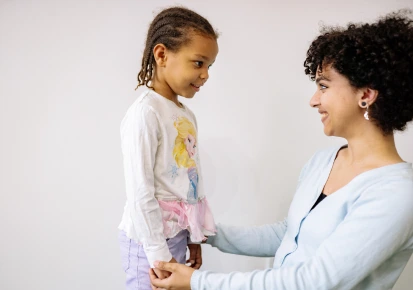 A counsellor kneeling to speak warmly with a young child